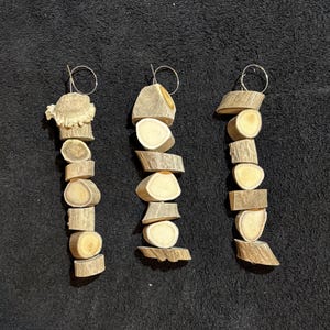 May include: Three antler ornaments, each with a different arrangement of antler slices, are strung together with a silver wire loop. The antler slices are a light brown color and have a natural, rustic look.