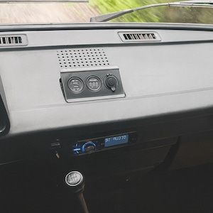 Könnte beinhalten: Innenansicht eines Oldtimer-Armaturenbretts. Das schwarze Armaturenbrett zeigt ein Radio, Anzeigen und einen Schalthebel. Das Radio zeigt "BT AUDIO". Das Bild stammt von CarCulture Cyprus.