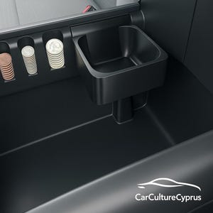 May include: A black car console featuring coin holders and a small storage bin. The console is situated beside a grey car seat. Various coins are visible in the coin holders.