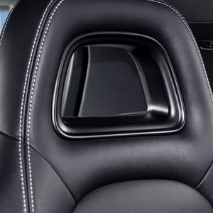 May include: Close-up of a black leather car seat headrest with white stitching. The headrest has a unique design with a rectangular opening in the center. The seat appears to be in excellent condition.