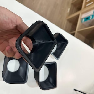 May include: A set of four black, funnel-shaped plastic components with a square outer rim and a circular inner opening. Each piece features a tapered design that narrows from the square frame toward the center hole, showing a smooth finish.