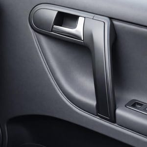 May include: Close-up of a car door interior. The door panel is dark gray with a textured surface. A silver door handle and a black armrest are visible. The image includes the text "CarCulture Cyprus".