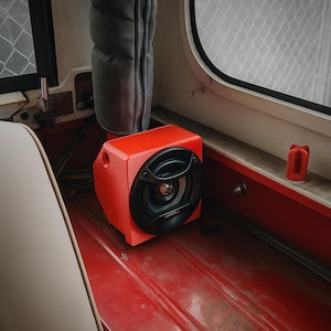 May include: A red speaker box with a black speaker is inside a vehicle. The speaker is mounted on a red surface. The text "CAR CULTURE CYPRUS" is visible in the upper portion of the image.