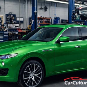 May include: A bright green Maserati SUV parked inside a car repair shop. The vehicle has a sleek design with silver rims and tinted windows. The background shows tools and equipment, suggesting a professional automotive service environment.