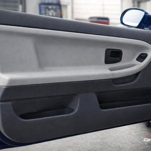May include: A blue car door panel with a light gray upper section and a dark gray lower section. The panel includes a door handle, window controls, and a speaker. A side mirror is visible.