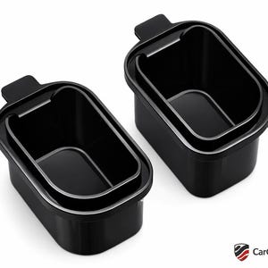 May include: Two black rectangular storage containers with a silver trim and a small handle. The containers are nested, set against a white background. Each container has a rectangular shape.