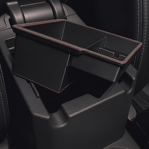 May include: Black car console organizer with a red stitched trim. The organizer is divided into compartments and fits into the center console of a vehicle. The image shows the organizer in place, with the text "CarCulture Cyprus" at the bottom.