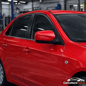 May include: A red sedan car with black window frames and side mirror. The car is parked inside a garage. The car has a logo on the side and the text "CarCultureCyprus" at the bottom right.