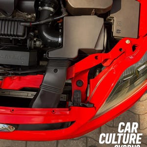 May include: A close-up of a car engine bay with a red bonnet. The engine components are visible, including a black air intake and various mechanical parts. The text "CAR CULTURE" is displayed in white.