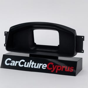 Può includere: Una cornice nera per il cruscotto dell'auto con un'apertura rettangolare, montata su una base nera. La base presenta il testo "CarCulture Cyprus" in lettere bianche e rosse. La cornice ha delle linguette di montaggio.