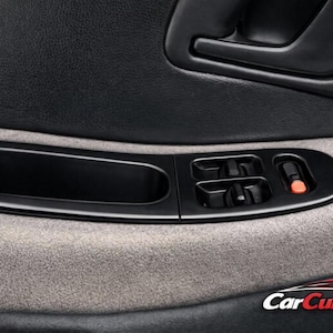 Puede incluir: Primer plano de un panel de puerta de coche con un tirador negro, controles de ventana y un botón de bloqueo. El panel es negro y gris, con una tela texturizada y un acabado liso y brillante.