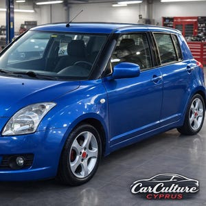 May include: A blue Suzuki Swift hatchback car with silver wheels and red accents. The car is parked inside a garage with the Car Culture Cyprus logo in the bottom right corner.