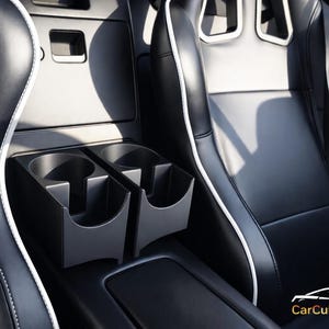 Puede incluir: Interior de coche con asientos de cuero negro y ribetes blancos. Incluye un portavasos integrado. El salpicadero y la consola también son negros. Diseño interior de coche limpio y moderno.