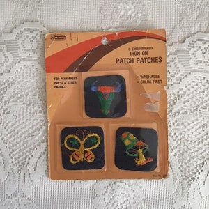 May include: A package of three iron-on patch patches. The patches feature a bull skull, a butterfly, and a mushroom. The package is orange and brown with the text "3 Embroidered Iron On Patch Patches" and "Washable Color Fast".