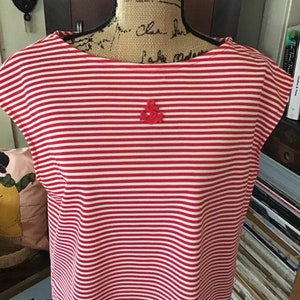 Peut inclure: Chemise à manches courtes à rayures rouges et blanches avec une petite ancre rouge brodée sur le devant.