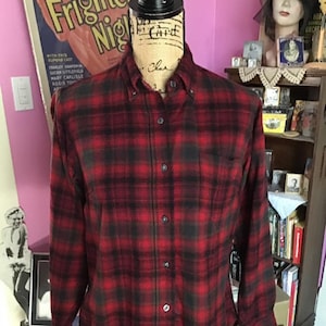 Peut inclure: Une chemise en flanelle à carreaux rouge et noir avec un col boutonné et des manches longues.