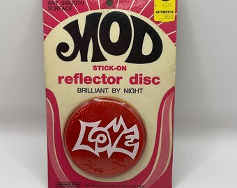 May include: Red reflective sticker with the word "LOVE" in white letters. The sticker is packaged on a card with the words "MOD STICK-ON reflector disc BRILLIANT BY NIGHT".