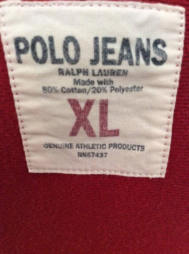 May include: White tag with black text that reads "POLO JEANS RALPH LAUREN Made with 80% Cotton/20% Polyester XL GENUINE ATHLETIC PRODUCTS RN87437"