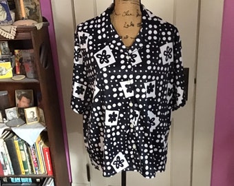 May include: A black and white short-sleeved button-up shirt with a polka dot and floral pattern.