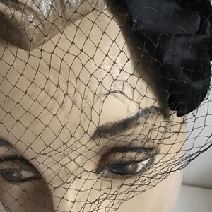 Puede incluir: Un sombrero de terciopelo negro con velo de red negro. El sombrero se lleva en la cabeza de un maniqu&iacute;.