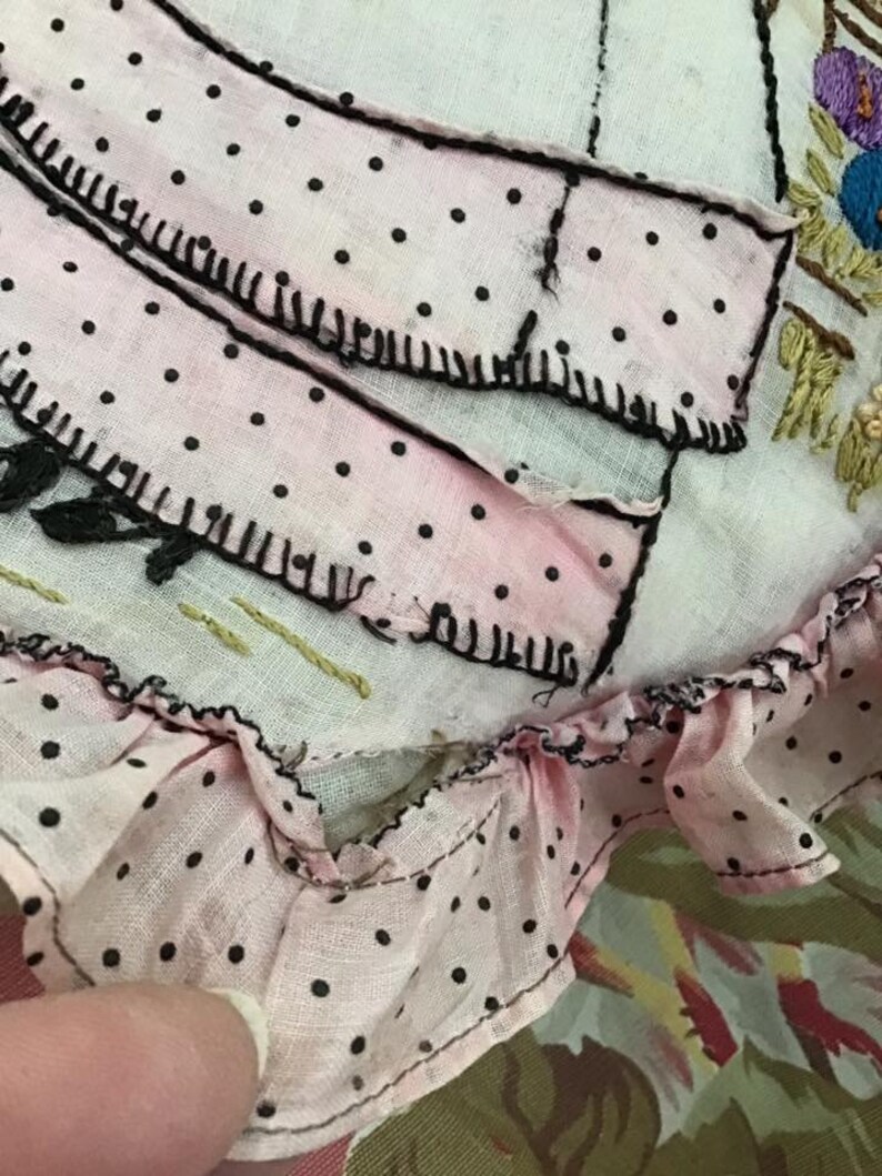 K&ouml;nnte beinhalten: Ein rosa Stoff mit schwarzen Punkten und einem gekr&auml;uselten Rand. Der Stoff ist mit schwarzem Garn gen&auml;ht und hat einen wei&szlig;en Hintergrund.