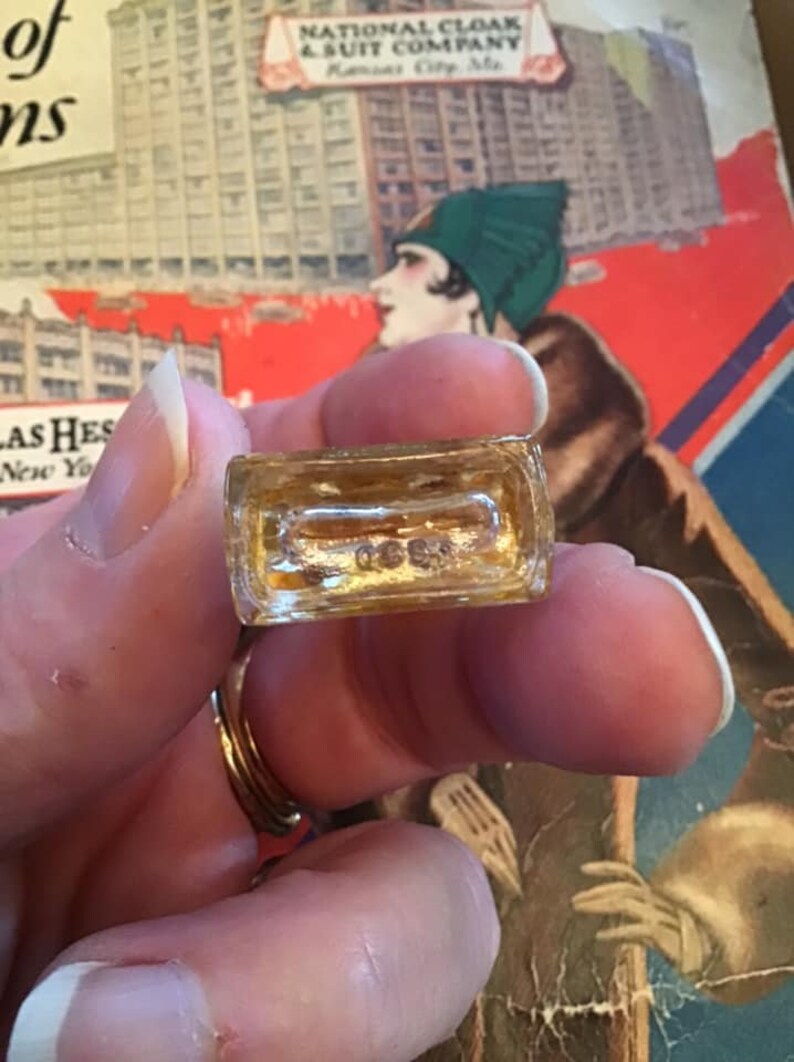 Puede incluir: Una peque&ntilde;a base rectangular de frasco de perfume de vidrio transparente con una marca en relieve en la parte inferior que dice 0689. El vidrio es transparente con un ligero tono &aacute;mbar, mostrando un interior hueco y un borde grueso.