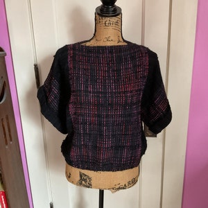 May include: Black and pink short-sleeved sweater with a textured woven design.