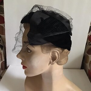 Puede incluir: Un sombrero de terciopelo negro con velo de red negro. El sombrero se lleva en la cabeza de un maniqu&iacute;.