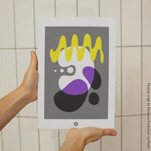 Könnte beinhalten: Ein gerahmter Kunstdruck mit einem abstrakten Design auf grauem Hintergrund. Das Design umfasst gelbe, weiße, violette und schwarze organische Formen. Der Druck wird von zwei Händen vor einem weißen Kachelhintergrund gehalten.