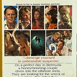 May include: A paperback book with a yellow and white cover featuring images of actors. The cover text includes "Soon to be a major motion picture" and a synopsis about a honeymooning couple diving into reefs.