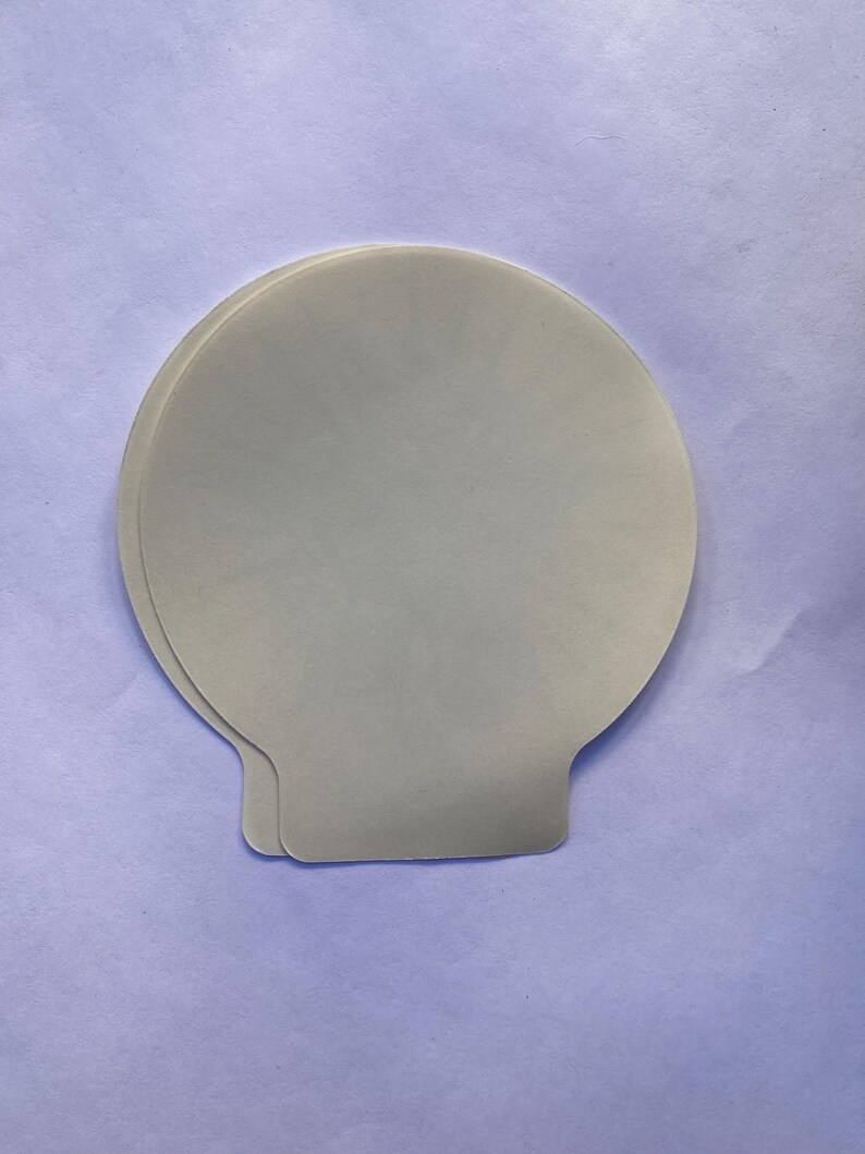 May include: Two white, round, paper baking cups with a scalloped edge.