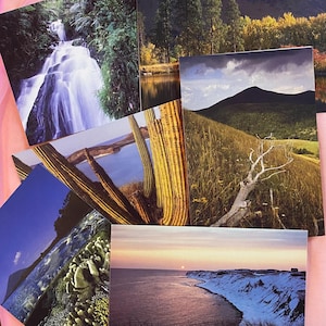 Peut inclure: Plusieurs photographies de paysages présentant diverses scènes naturelles. Les images incluent une cascade, un lac avec des couleurs d'automne, une chaîne de montagnes, un paysage désertique avec des cactus et une vue côtière au coucher du soleil. Les photos sont imprimées sur papier glacé.