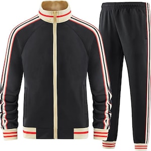 Puede incluir: Chándal negro con rayas blancas y rojas. La chaqueta tiene cierre de cremallera y cuello alto. El pantalón tiene cintura elástica.
