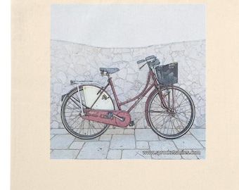 May include: A cream tote bag with a watercolour illustration of a burgundy bicycle with a basket. The bicycle is parked in front of a textured white wall and a brick-paved pavement. The bag has long, matching handles.