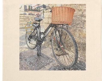 May include: Cream tote bag with a digitally-rendered image of a bicycle with a wicker basket. The bicycle is parked against a stone wall. The image has a vintage, artistic style.