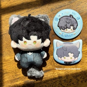May include: A plush doll with black hair and cat ears, wearing a gray suit, and a gray tail. Two light blue badges with cartoon illustrations of the doll are also present. One badge is round with the name "Lishen", and the other is cat-shaped with the word "meow".