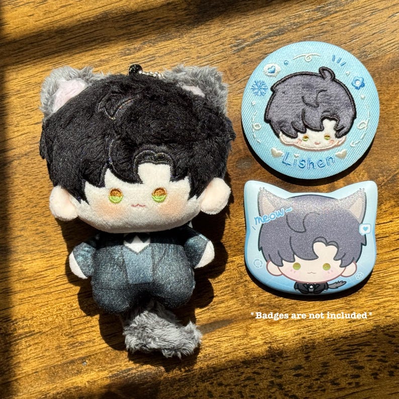 May include: A plush doll with black hair and cat ears, wearing a gray suit, and a gray tail. Two light blue badges with cartoon illustrations of the doll are also present. One badge is round with the name "Lishen", and the other is cat-shaped with the word "meow".