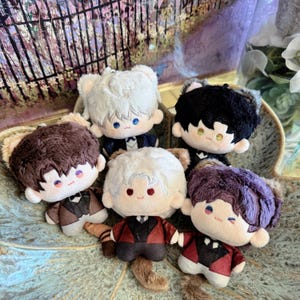 May include: A collection of plush dolls with anime-style features. Each doll has a unique hairstyle in colors like white, black, brown, and purple. They wear miniature suits with bow ties and have cat-like ears. The dolls are arranged in a decorative bowl.