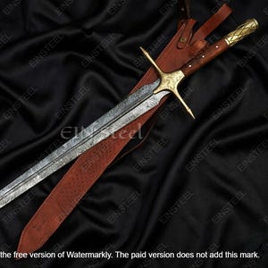 May include: A long, ornate sword with a patterned blade and gold-colored hilt, resting in a brown leather sheath. The sword features a crossguard and a wooden handle. The background is a dark, textured fabric.