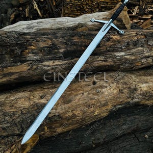 May include: A long, silver sword with a black handle and crossguard, resting on a weathered wooden log. The blade is sharp and reflective, with a pointed tip. The crossguard has a decorative design. The background features more wood.
