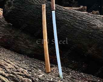 May include: A long, slender sword with a polished silver-colored metal blade and a straight wooden handle, positioned next to its matching wooden scabbard. The sword features a simple, unadorned design with a sharp, slightly curved tip.