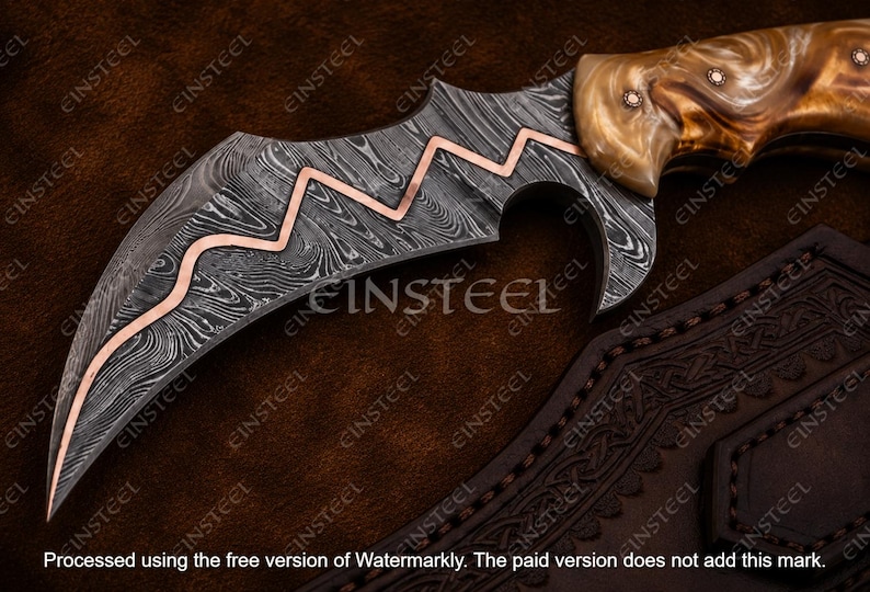 Pu&ograve; includere: Un coltello curvo con lama in acciaio damasco a motivi, caratterizzato da un intarsio in rame a zig-zag. Il manico &egrave; realizzato in materiale lucidato e marmorizzato nei toni del marrone e crema, fissato con due perni metallici.