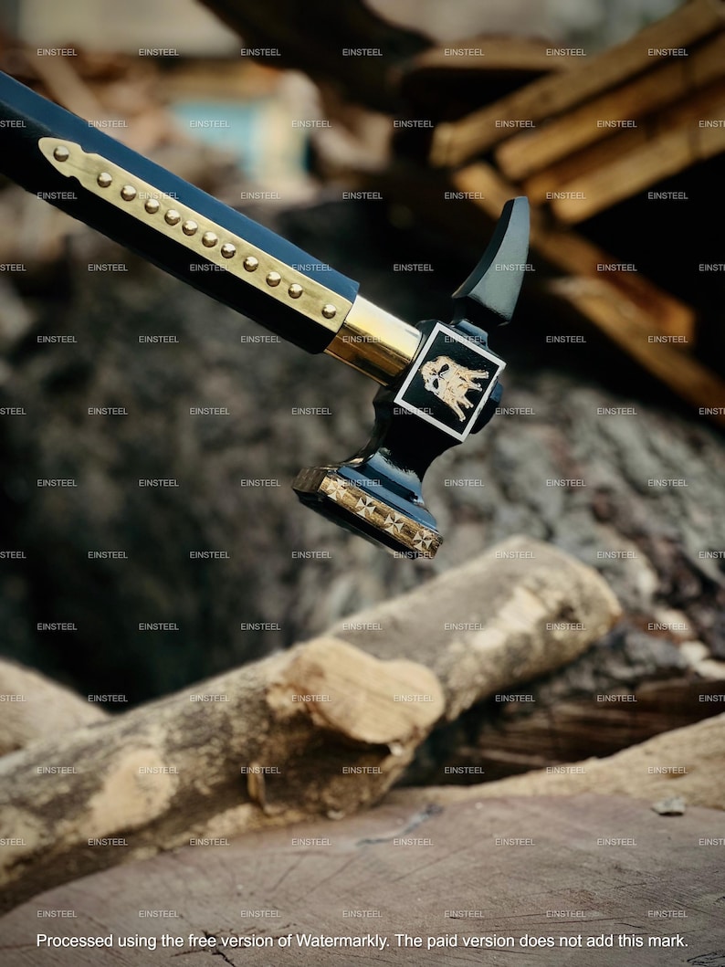 May include: A black and gold hammer with a decorative handle and head. The hammer features a gold emblem and is positioned over a background of wooden logs. The handle is adorned with gold accents and rivets.