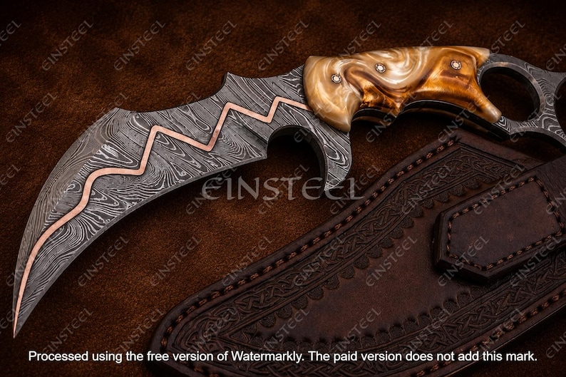 Pu&ograve; includere: Un coltello a lama curva con motivo in acciaio Damasco e un inserto a zigzag in rame lungo il dorso. Il manico &egrave; realizzato in un materiale marmorizzato marrone chiaro con tre rivetti metallici. &Egrave; incluso un fodero in pelle marrone scuro.