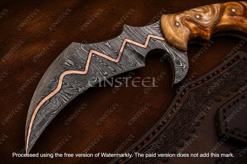 Pu&ograve; includere: Un coltello a lama curva con un motivo in acciaio Damasco scuro e un intarsio in rame a zigzag lungo il dorso. Il manico &egrave; realizzato in materiale marmorizzato marrone chiaro con piccoli rivetti metallici. &Egrave; visibile un fodero in pelle.