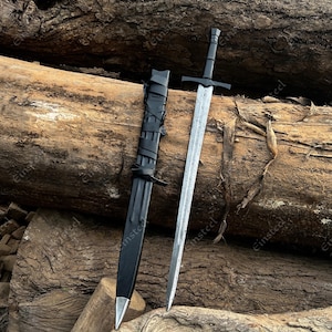 May include: A long sword with a double-edged, patterned steel blade and a black hilt, accompanied by a matching black scabbard featuring a silver-toned metal tip and black leather straps wrapped around the upper portion of the sheath.