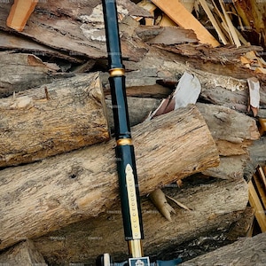 May include: A black and gold hammer with a long handle and a square head. The handle is black with gold accents and a series of small gold rivets. The hammer head features a decorative emblem.