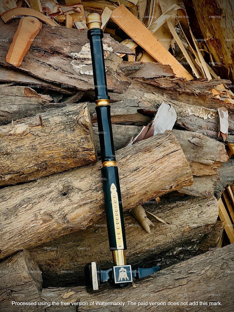 May include: A black and gold hammer with a long handle and a square head. The handle is black with gold accents and a series of small gold rivets. The hammer head features a decorative emblem.