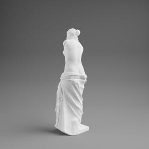 May include: A white sculpture of a classical female figure, depicting the torso and lower body. The figure is draped in fabric, with the upper body and arms missing. The sculpture is set against a gray background.