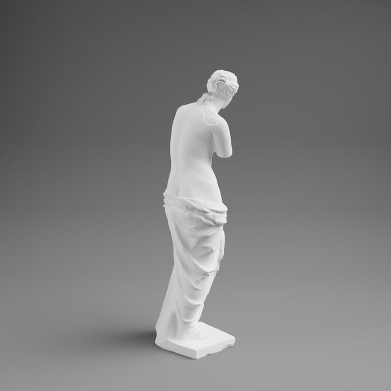May include: A white sculpture of a classical figure, viewed from the back. The figure is draped in fabric and stands on a rectangular base. The sculpture has a smooth, matte finish and is set against a gray background.
